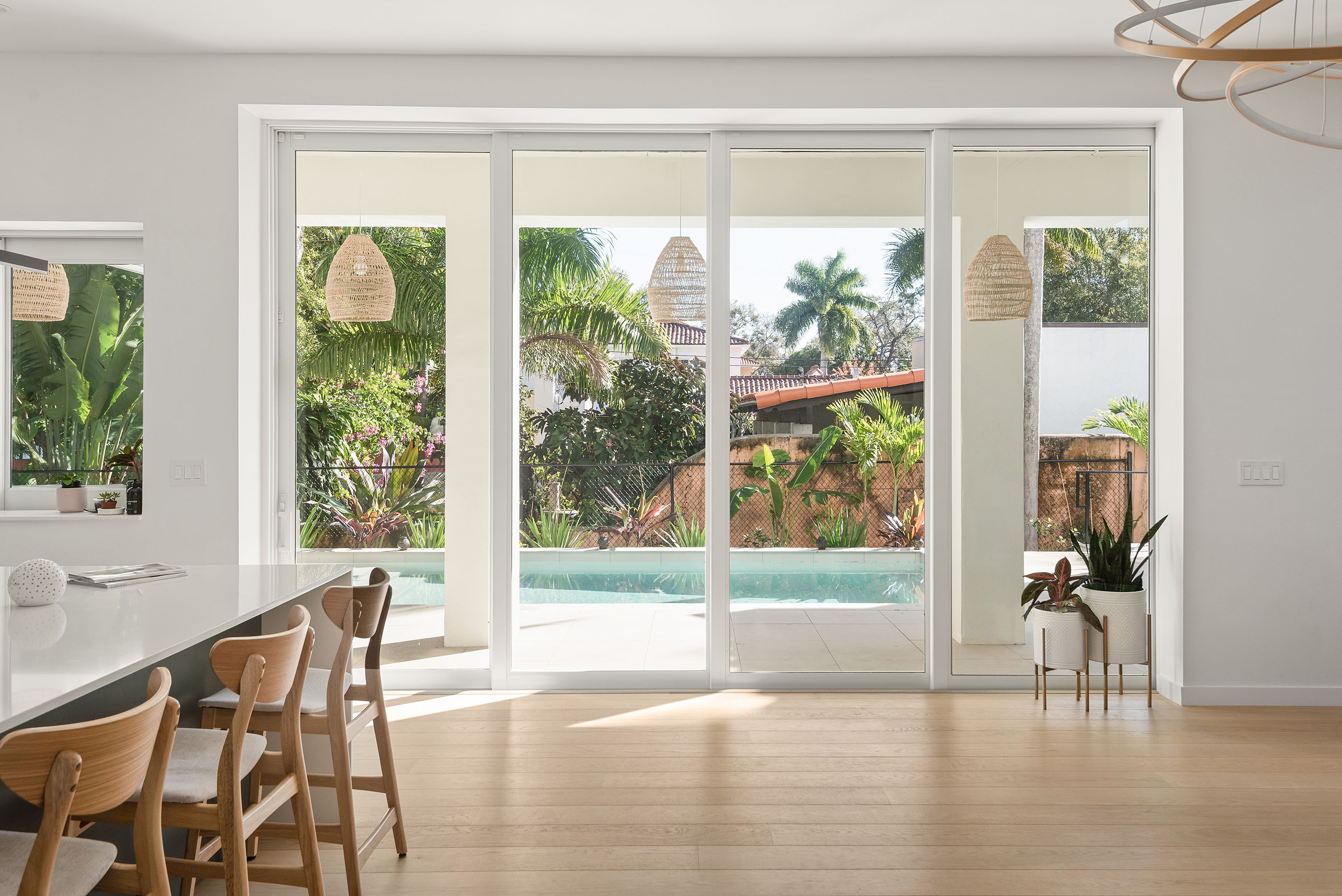 Light-filled interior with floor-to-ceiling windows overlooking pool and tropical garden