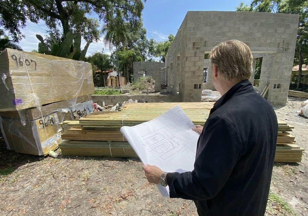 Builder reviewing architectural plans at active construction site
