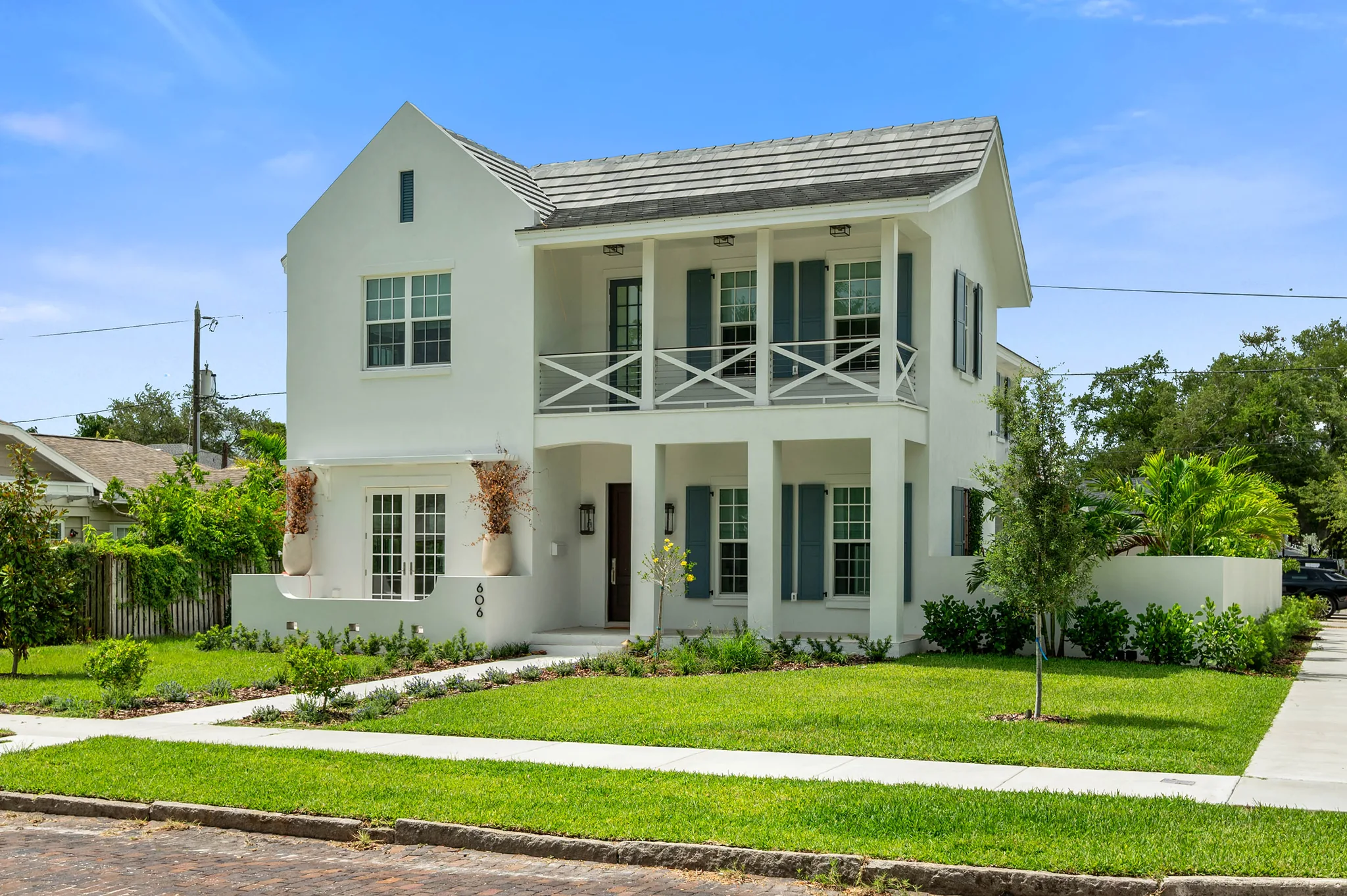 Corner view of white coastal colonial custom home with double veranda and Bermuda-blue shutters
