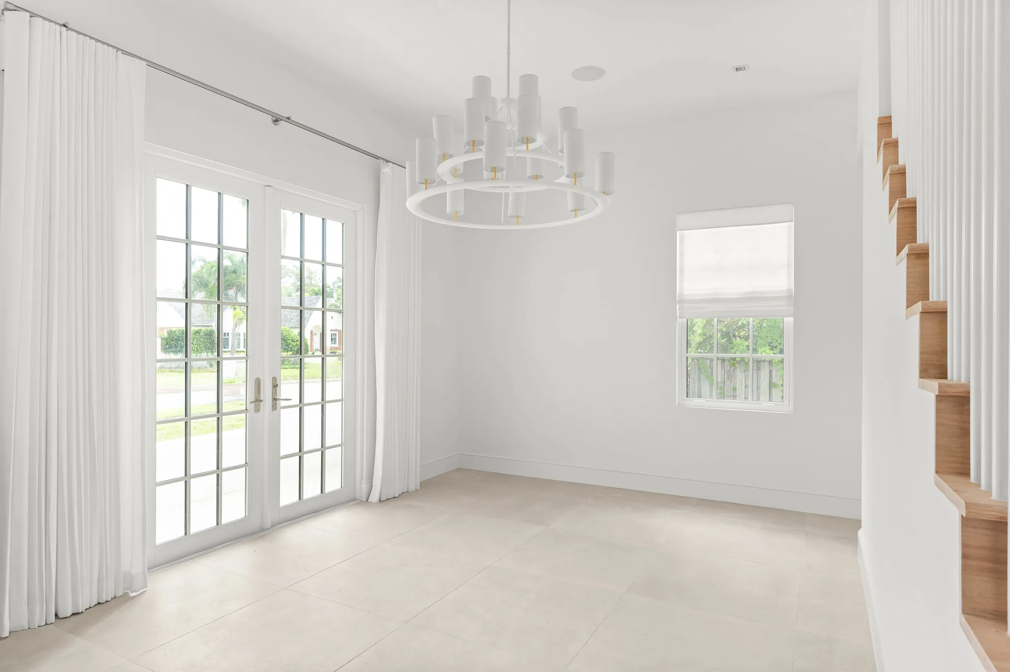 Dining room with tiered chandelier and French doors to the front porch