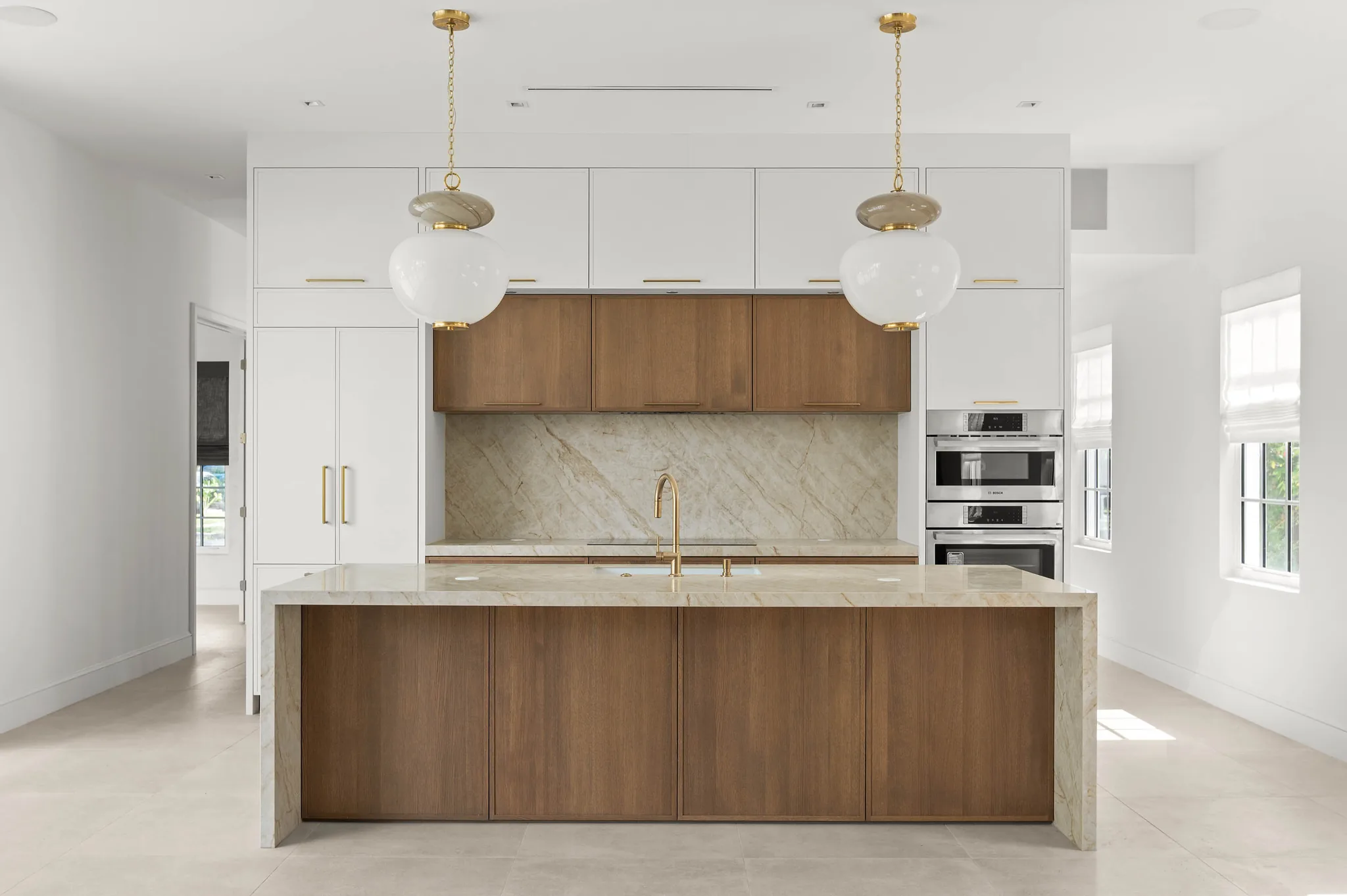 Chef's kitchen with quartzite waterfall island, white oak cabinetry, and glass-globe pendants