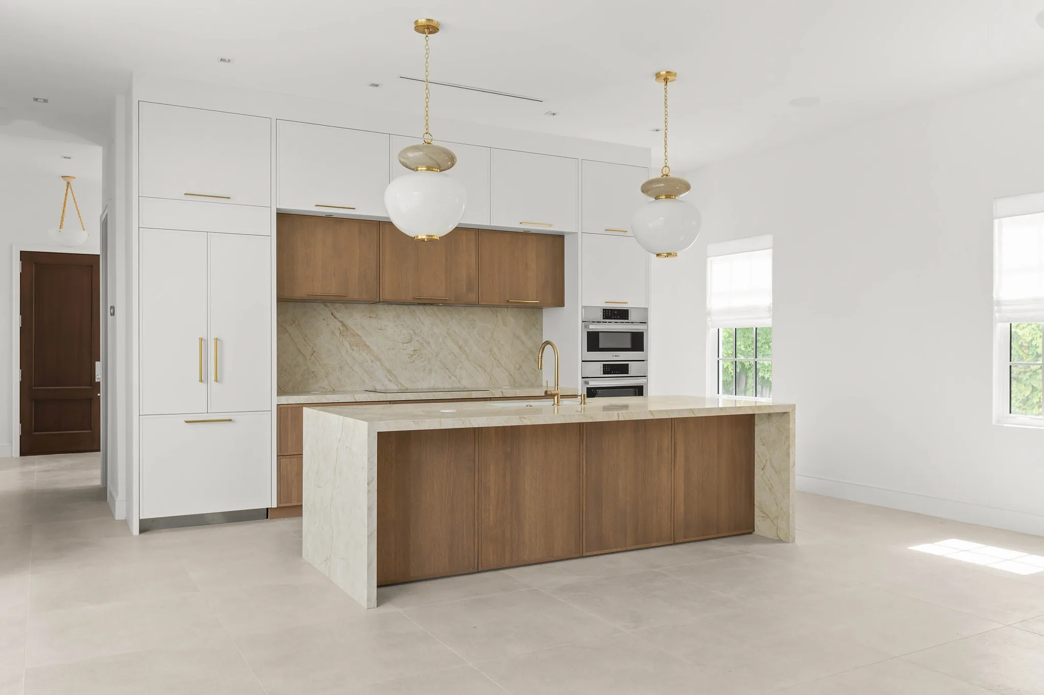 Kitchen with full-height quartzite backsplash and two-tone cabinetry