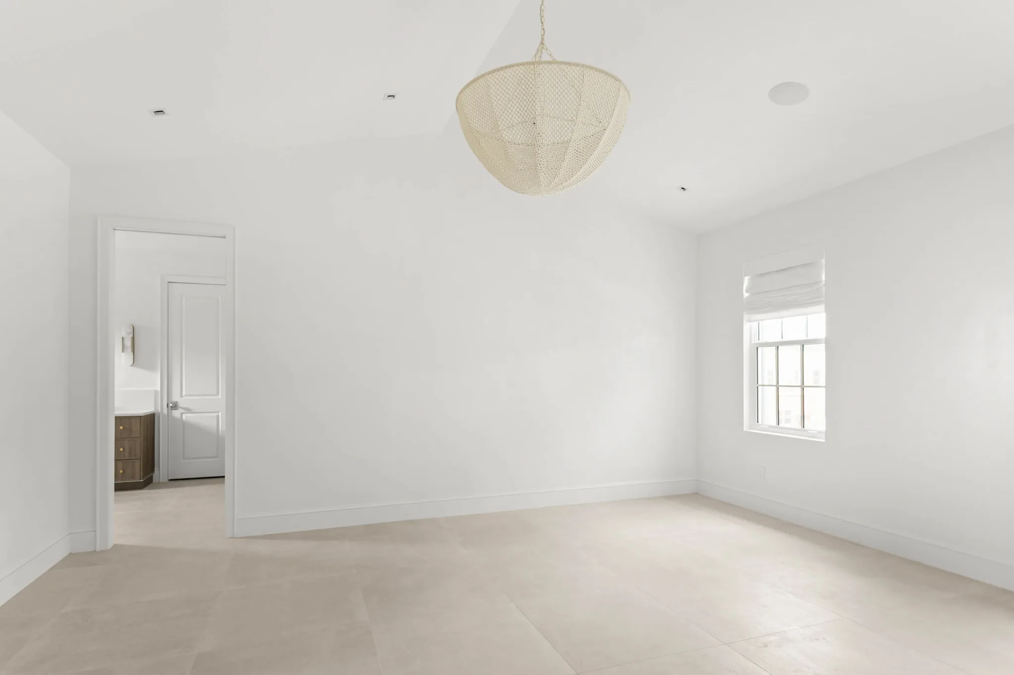 Primary bedroom with vaulted ceiling and woven pendant