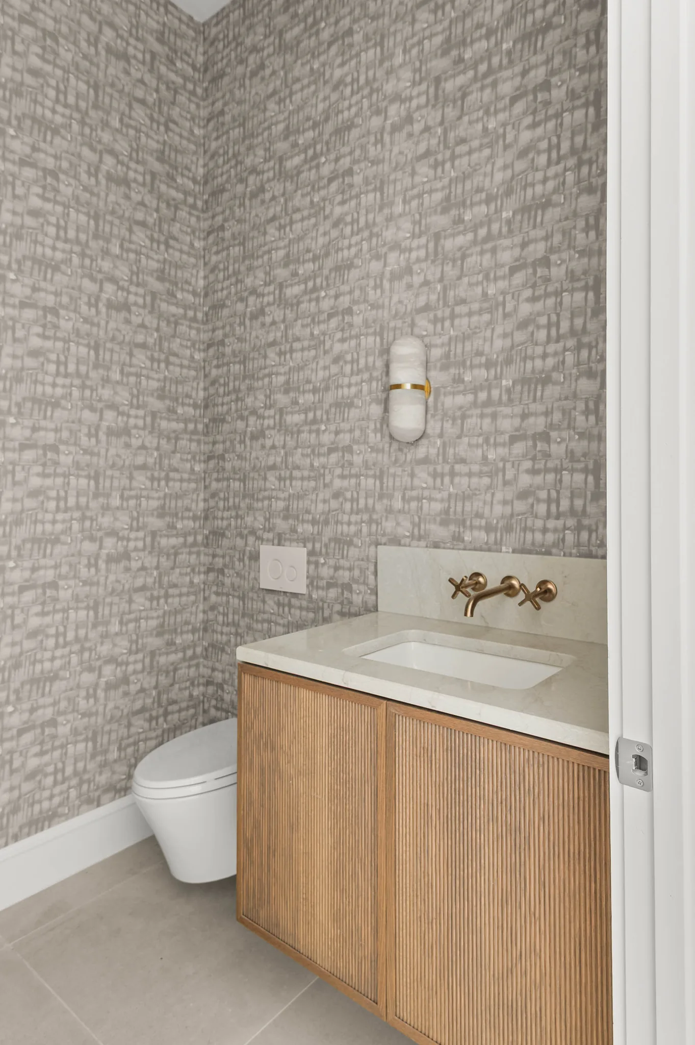 Powder room with textured wallpaper and floating reeded oak vanity