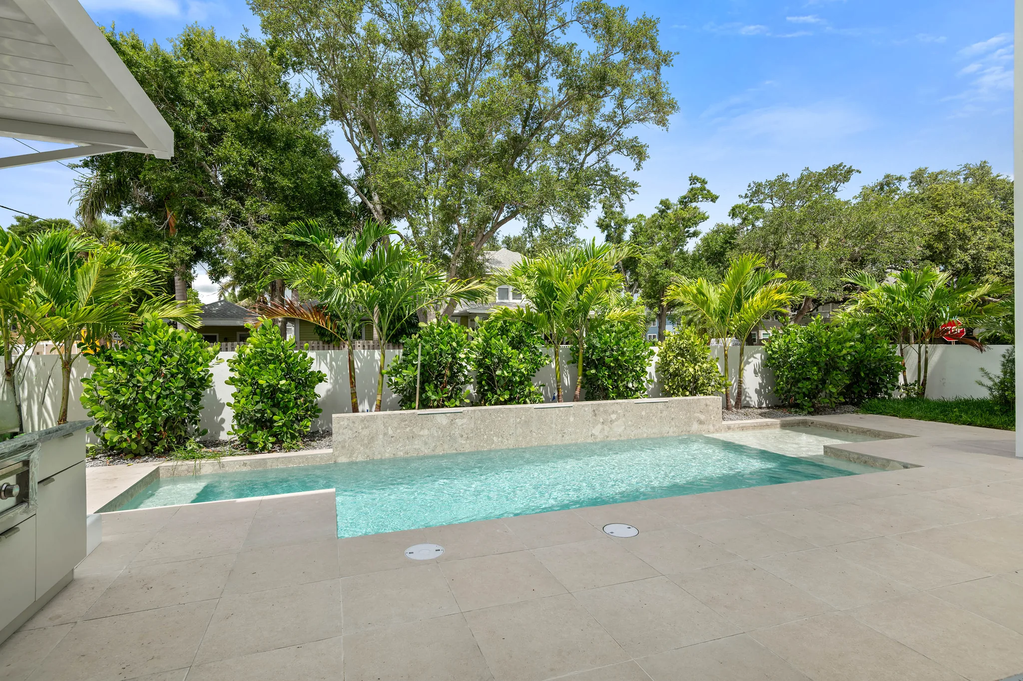 Pool with raised stone fountain wall and tropical landscaping