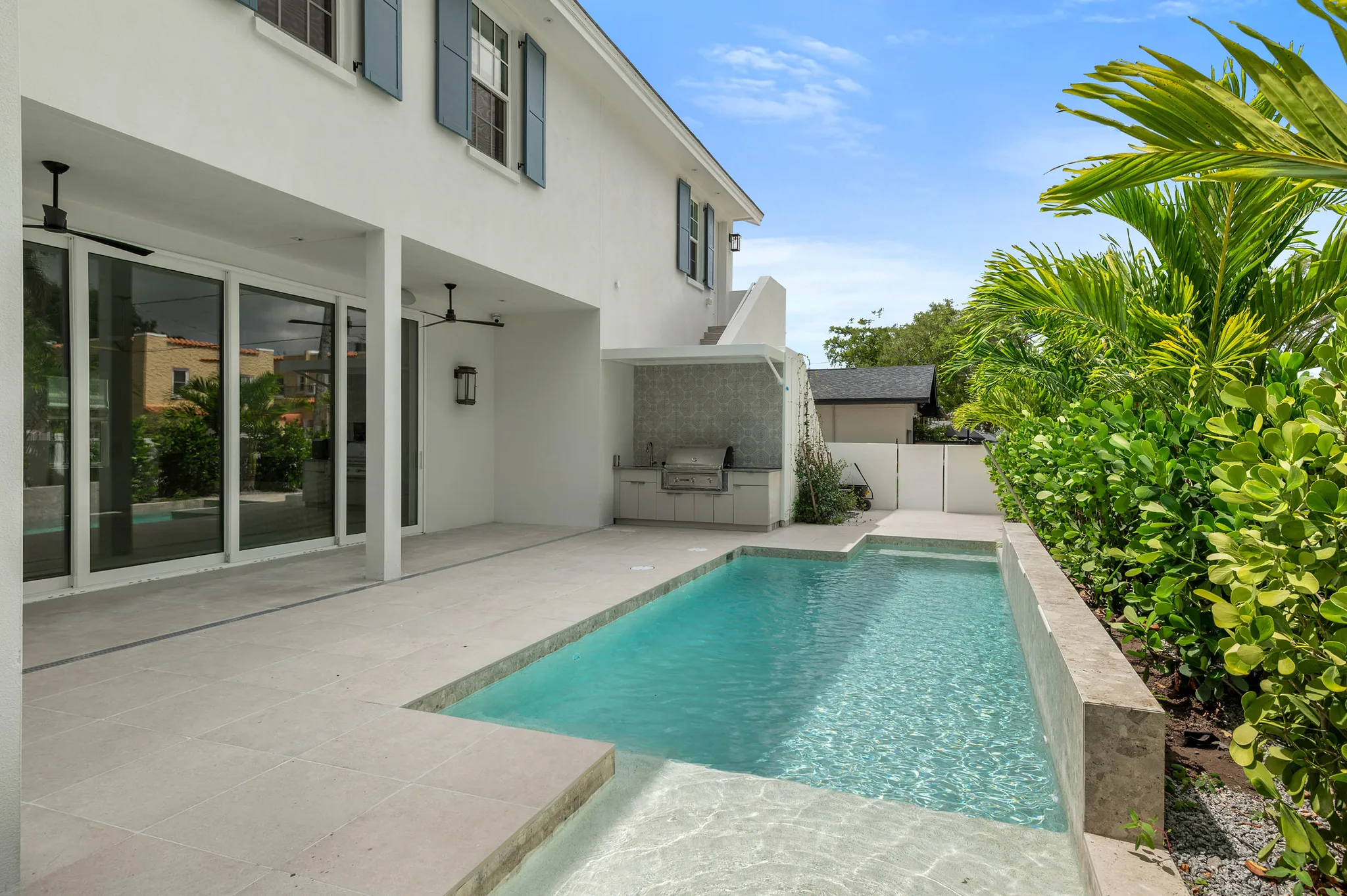 Pool running alongside the covered lanai and outdoor kitchen